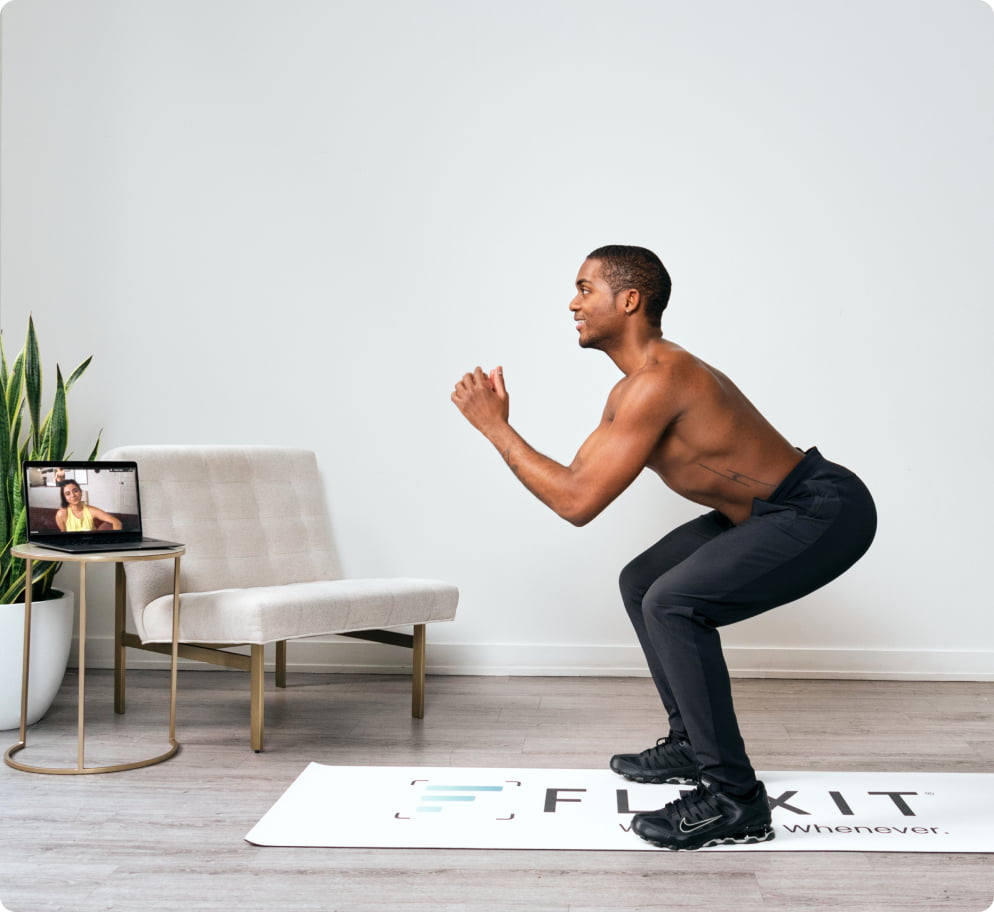 Man squatting with a trainer on a laptop screen